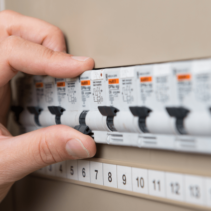 person flicking circuit breaker on switchboard